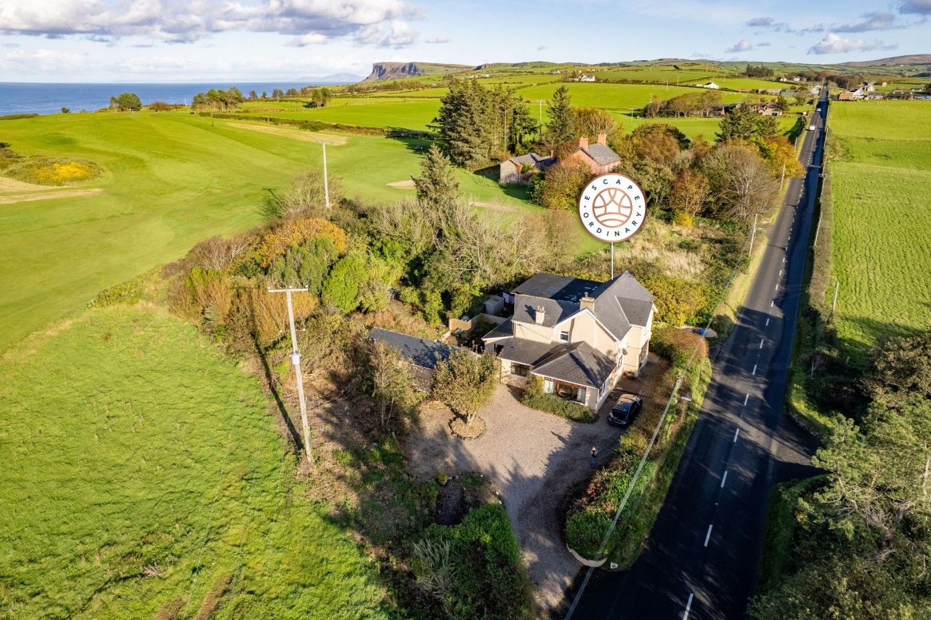 Ein ländliches Anwesen mit einem großen Haus, einer Auffahrt und einem Golfplatz im Hintergrund.