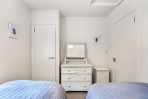 A bedroom with two beds, a dresser, a mirror, and two framed pictures on the wall. - Horseshoe Cottage by Escape Ordinary (Derrygonnelly)