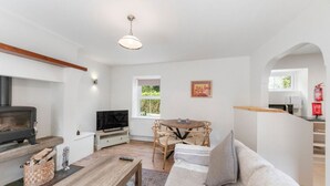 A living room with a fireplace, a television, a dining table with chairs, and a sofa. - Horseshoe Cottage by Escape Ordinary (Derrygonnelly)