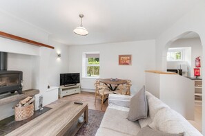 A living room with a fireplace, a television, a dining table with chairs, and a sofa. - Horseshoe Cottage by Escape Ordinary (Derrygonnelly)