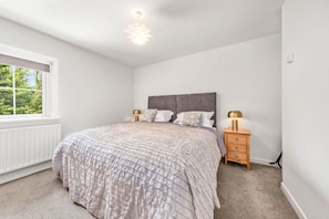 A bedroom with a bed, bedside tables, a window, and a radiator. - Horseshoe Cottage by Escape Ordinary (Derrygonnelly)