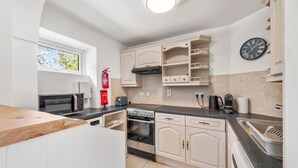 A modern kitchen with white cabinetry, a built-in oven, a stove, a microwave, a toaster, and a coffee maker. - Horseshoe Cottage by Escape Ordinary (Derrygonnelly)