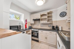 A modern kitchen with white cabinetry, a built-in oven, a stove, a microwave, a toaster, and a coffee maker. - Horseshoe Cottage by Escape Ordinary (Derrygonnelly)