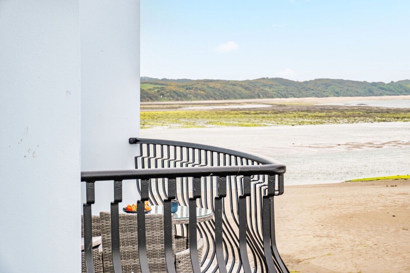 A balcony with a view of a beach and distant hills.
