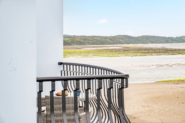 A balcony with a view of a beach and distant hills. - The Lookout · Dundrum Bay · Balcony with Bay Views (Dundrum)