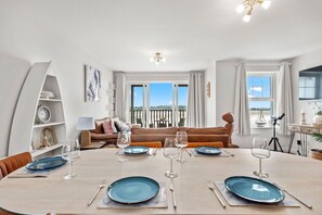 Een eetgedeelte met een ronde tafel voor vier personen, een bank op de achtergrond en een balkon met uitzicht.
