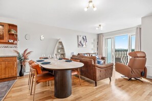 Ein modernes Wohnzimmer mit Essbereich, einer Couch, einem Sessel und einem Balkon mit Blick.
