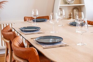A dining table set with plates and wine glasses, surrounded by leather chairs. - The Lookout · Dundrum Bay · Balcony with Bay Views (Dundrum)
