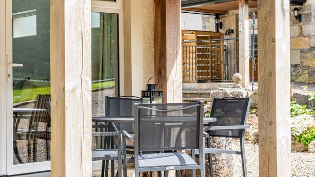An outdoor seating area with metal chairs and tables, a stone wall, and a wooden fence. - Orchard View Cottage | Escape Ordinary (Derrygonnelly)