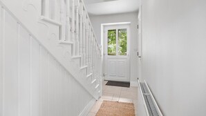 A white interior hallway with a staircase, a door, and a radiator. - Orchard View Cottage | Escape Ordinary (Derrygonnelly)
