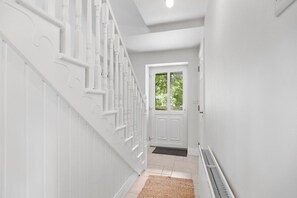 A white interior hallway with a staircase, a door, and a radiator. - Orchard View Cottage | Escape Ordinary (Derrygonnelly)