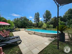 A backyard with a swimming pool, lounge chairs, and a covered patio area. - House with shared pool - 6 guests (Montignac-Lascaux)