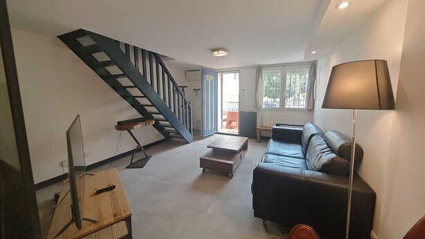 Ein Wohnzimmer mit Treppe, Sofa, Couchtisch und Lampe.