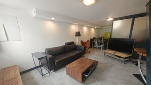 Ein modernes Wohnzimmer mit einer Couch, einem Couchtisch, einem Fernseher und einem Essbereich mit Stühlen.