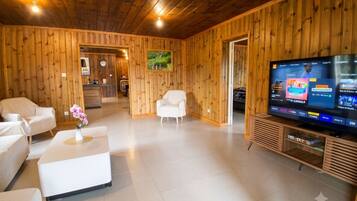 A modern living room with wooden paneling, a flat-screen TV, and a white sofa.