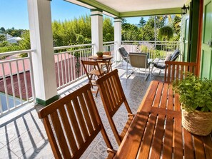 A covered outdoor seating area with wooden furniture and a view of the surrounding greenery. - Lodging with panoramic mountain view - 6 guests (Salazie)