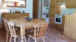 Una mesa de comedor de madera con seis sillas, un mueble de madera con estufa, y un espejo sobre la mesa.