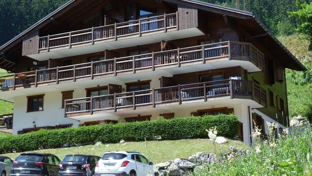 Una cabaña de madera de varios pisos con balcones, ubicada en una zona montañosa.