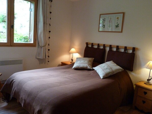 A bedroom with a large bed, two bedside tables, a window with curtains, and a framed picture on the wall. - Charming apartment in ArÃªches-Beaufort - 7 guests (Arêches-Beaufort)