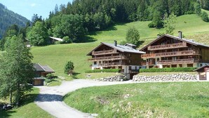 Un hotel de estilo chalet con varios balcones, situado en una zona montañosa bajo un cielo despejado.