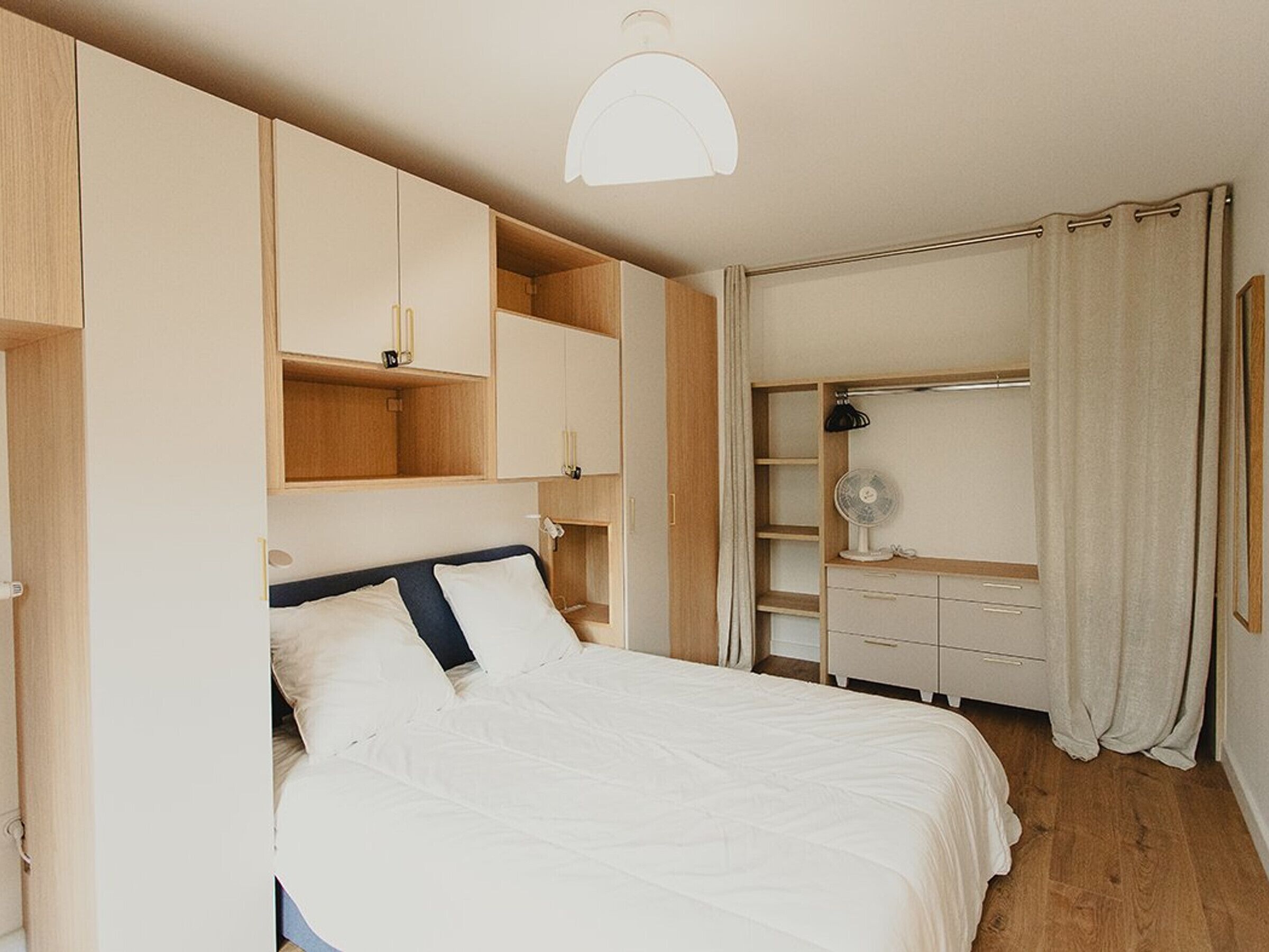 Un dormitorio con cama, estanterías empotradas, armario y ventilador de techo.