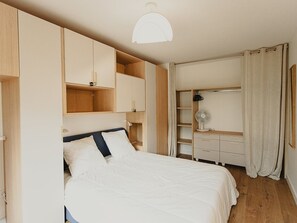 Une chambre à coucher comprenant un lit, des étagères intégrées, une armoire et un ventilateur de plafond.