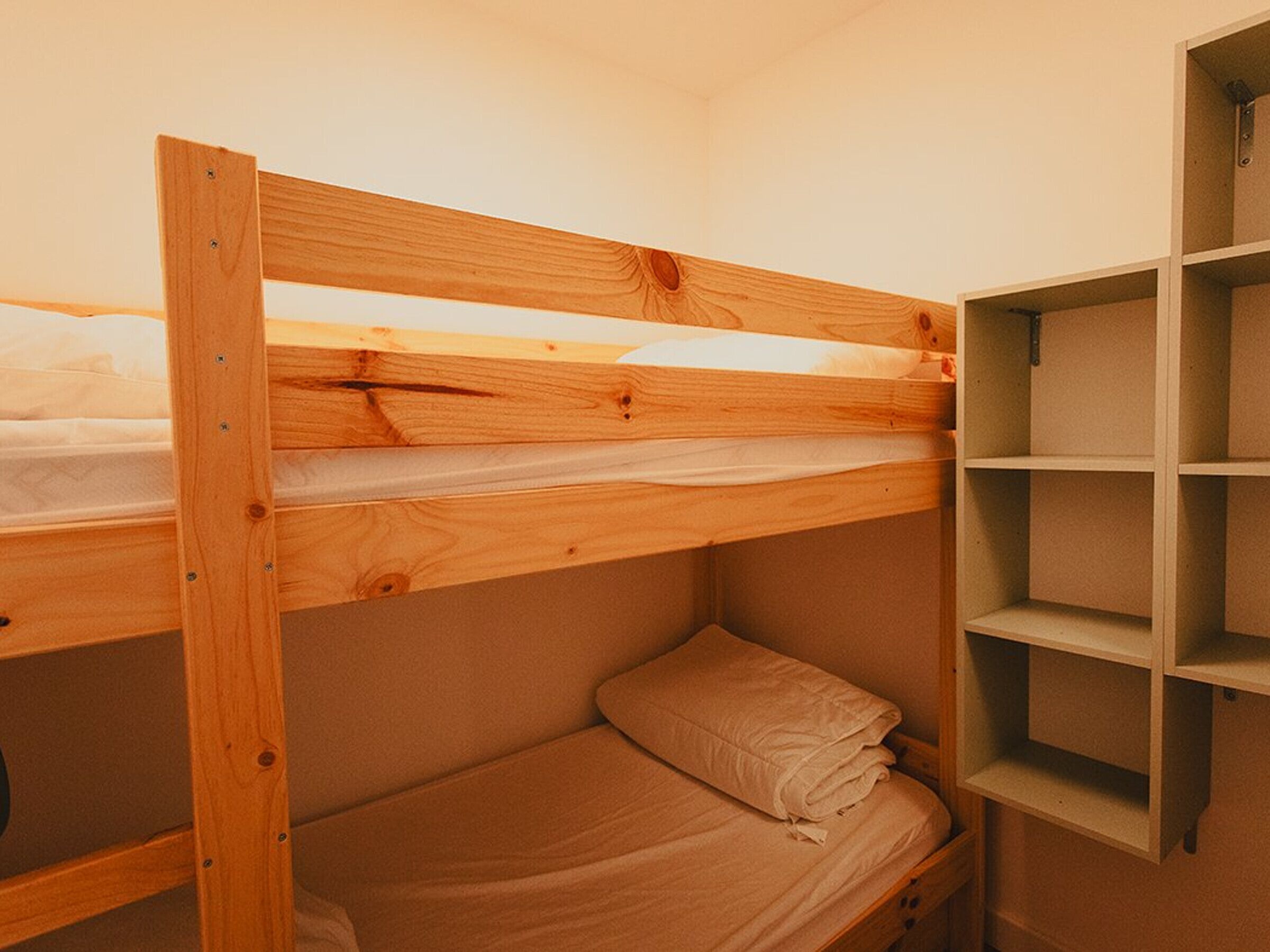 Een stapelbed met houten frame en een onderste bedplaats.
