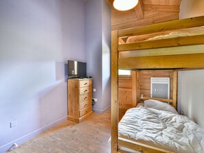 Ein Etagenbett mit Holz Kopfteil, eine Kommode aus Holz mit Schubladen und ein Fernseher darauf.