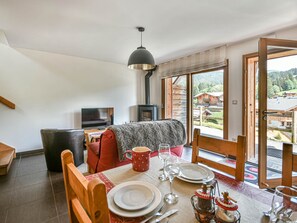 Ein Essbereich mit einem für zwei Personen gedecktem Tisch, einem Fernseher und einem Kamin.