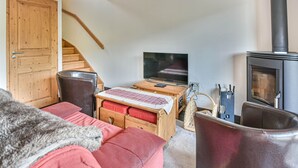 Ein gemütliches Wohnzimmer mit einer Couch, einem Holztisch, einem Fernseher und einem Kamin.
