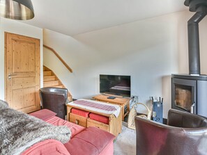 Ein gemütliches Wohnzimmer mit einer Couch, einem Holztisch, einem Fernseher und einem Kamin.