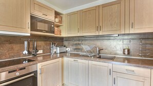 Eine moderne Küche mit Holzausstattung, Edelstahlgeräten und einem eingebauten Ofen.