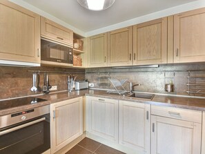Eine moderne Küche mit Holzausstattung, Edelstahlgeräten und einem eingebauten Ofen.