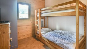 Ein Schlafraum mit Etagenbetten, einem Fenster, Holzwänden und einem Schminktisch.