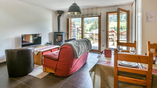 Ein gemütliches Wohnzimmer mit einer Couch, einem Fernseher, einem Kamin und einer Essecke für zwei Personen.