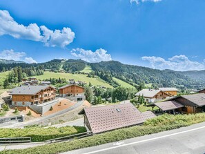 Ein Bergresort mit Holzhäusern, einer asphaltierten Straße und Blick auf die umliegenden Hügel.