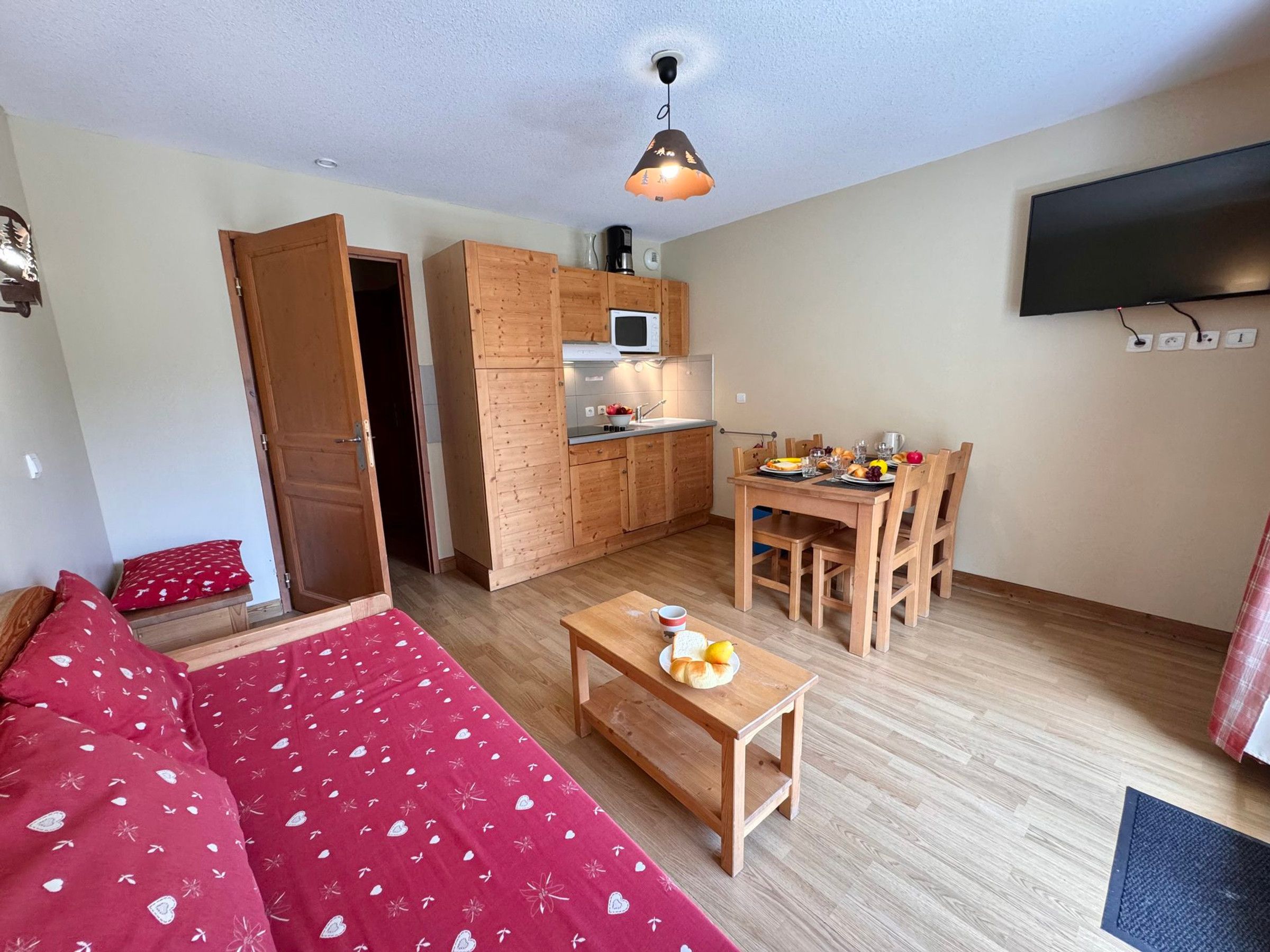 A compact living space with a kitchenette, a dining area, a sofa, and a television.