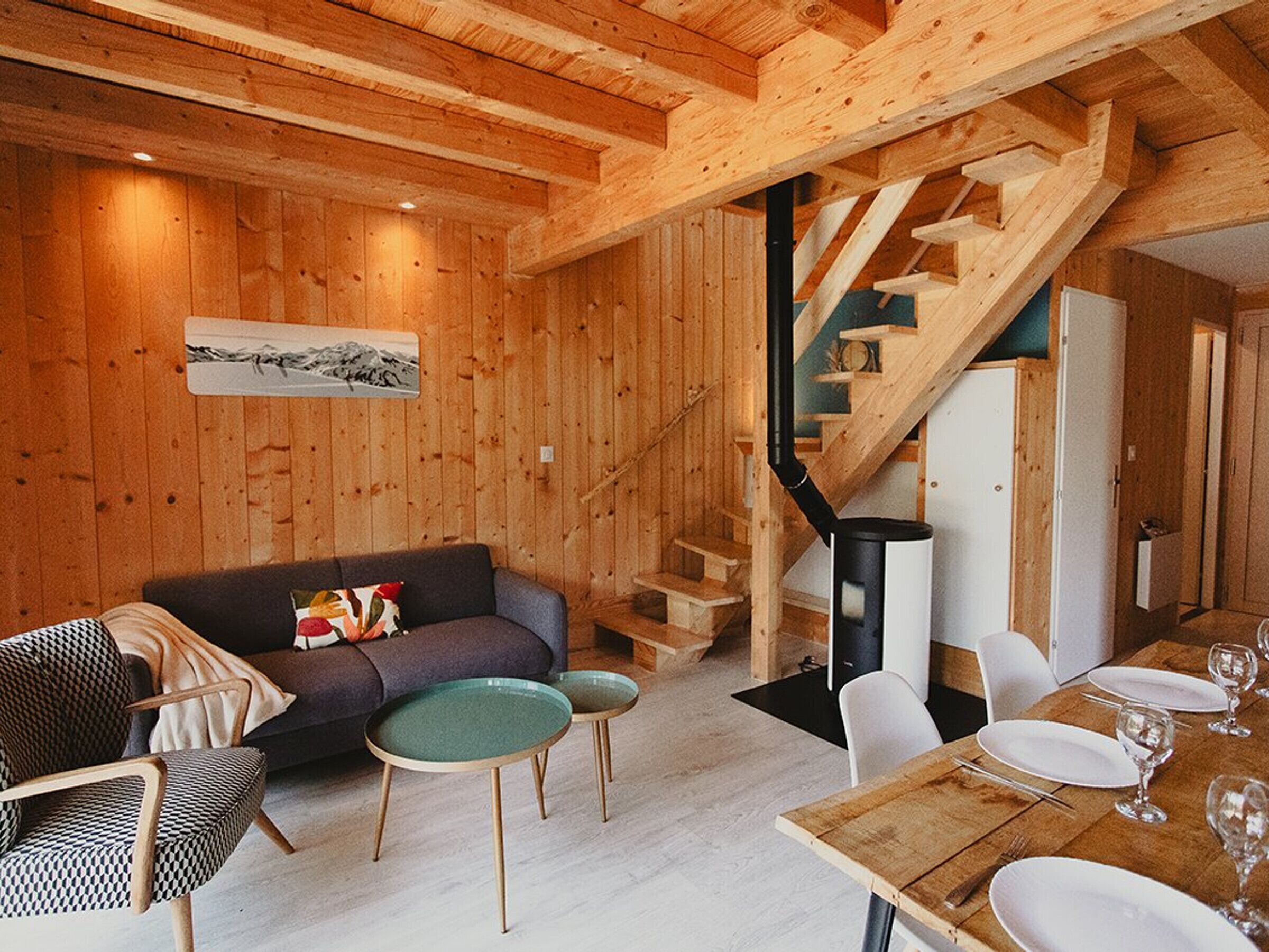 Un interior de madera con sofá, mesa de comedor, sillas y una escalera.