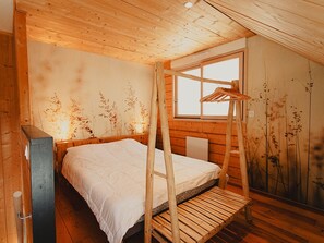 A wooden cabin bedroom with a bunk bed, a window, and a wall with a nature-themed mural.
