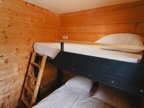 Ein Stockbett in einem Holzraum mit einer Leiter.