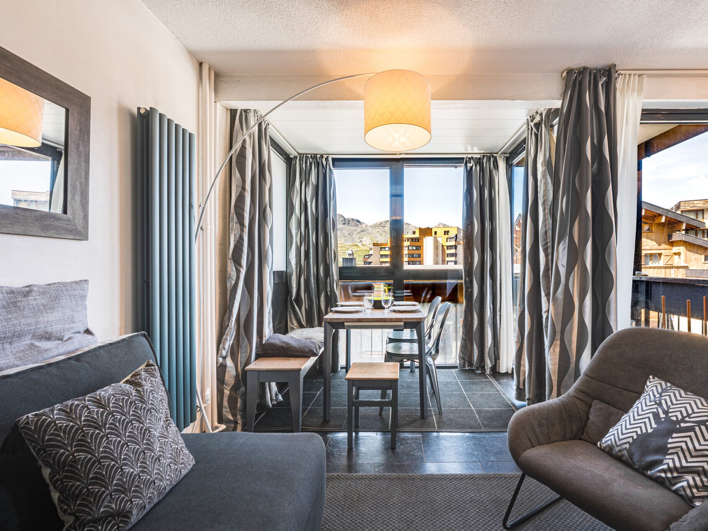Une chambre d’hôtel moderne dotée d’un coin repas, de grandes fenêtres et offrant une vue sur le paysage urbain.