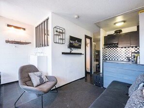 Ein modernes Interieur mit einer Sitzecke, einer Küchenzeile und einem an der Wand befestigten Fernseher.