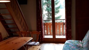 A room with a wooden table, benches, a sofa, and a staircase. - Cosy 2-Room Mezzanine Apartment, Sleeps 5, South-Facing Balcony, Near Linga Lift, Parking Included (Châtel)
