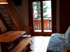 A room with a wooden table, benches, a sofa, and a staircase. - Cosy 2-Room Mezzanine Apartment, Sleeps 5, South-Facing Balcony, Near Linga Lift, Parking Included (Châtel)