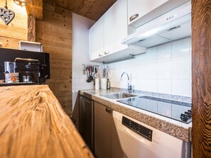 Eine Küche mit Holzausstattung, einer Edelstahlspüle und einer Kaffeemaschine.