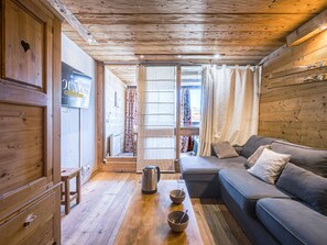 Ein gemütliches Blockhaus-Interieur mit Holzbalkendecke, einer Couch, einem Tisch mit Schüsseln und einem Schild an der Wand.