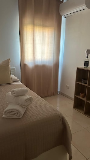 A hotel room with a bed, a shelf with toiletries, and a window with curtains. - B&B Iris pescara (Pescara)
