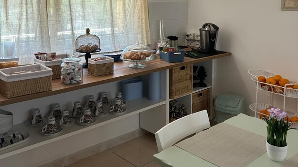 Una cocina con ventana, un reloj y diversos utensilios sobre la encimera.