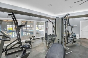 A gym with various exercise machines, a pool visible through the glass doors, and a door marked "EXIT". - Windward Pointe 1204 by Liquid Life (Orange Beach)