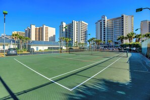 A tennis court with a net, surrounded by a fence, and adjacent to a parking area. - Windward Pointe 1204 by Liquid Life (Orange Beach)